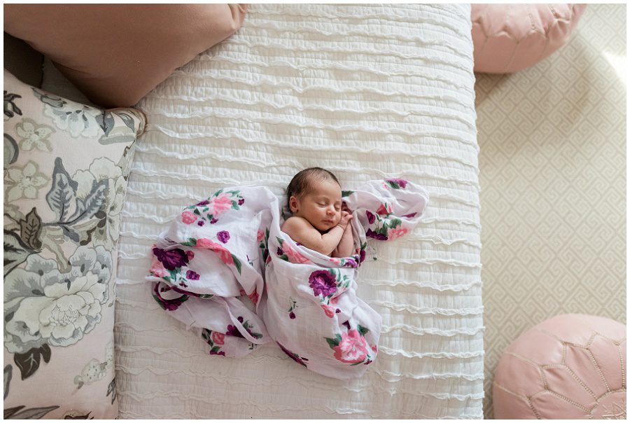 Newborn baby girl is lying on a day bed photographed from above looking down in her nursery.