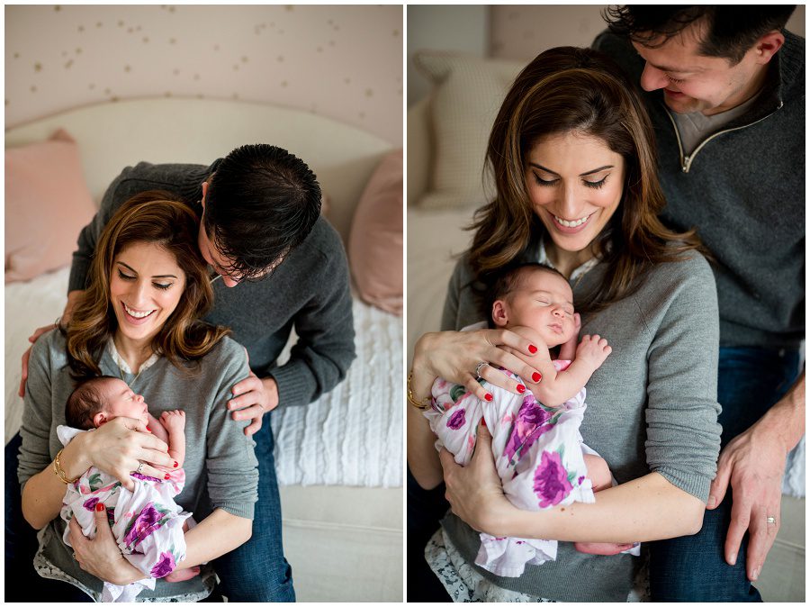 mother holding baby in home session on pink backless chairs vertical to parents holding sleeping newborn swaddled in blanket being embraced by father and smiling