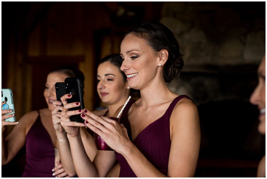 Bridesmaid taking photos of bride during prep