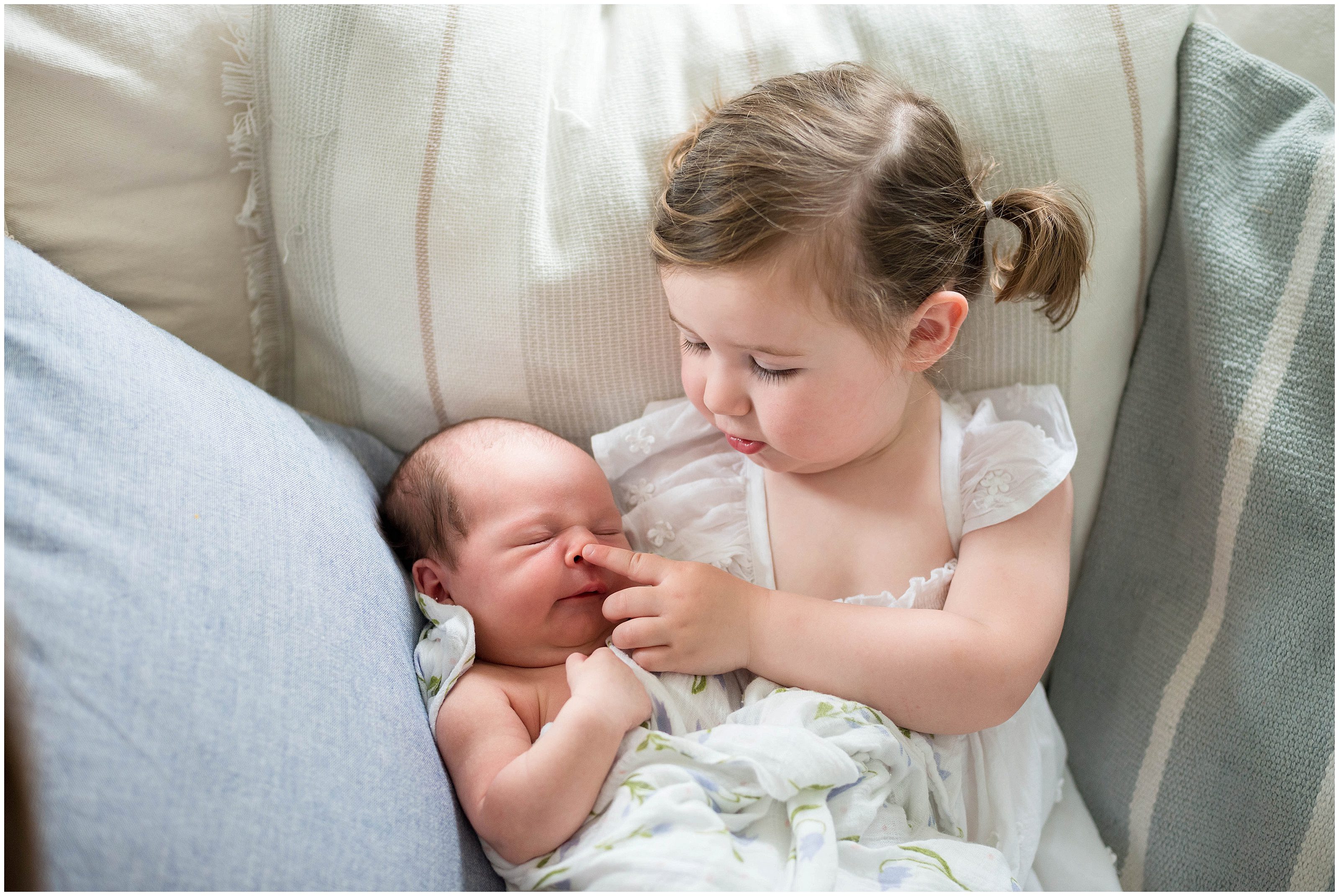 Big sister touching baby newborn's nose