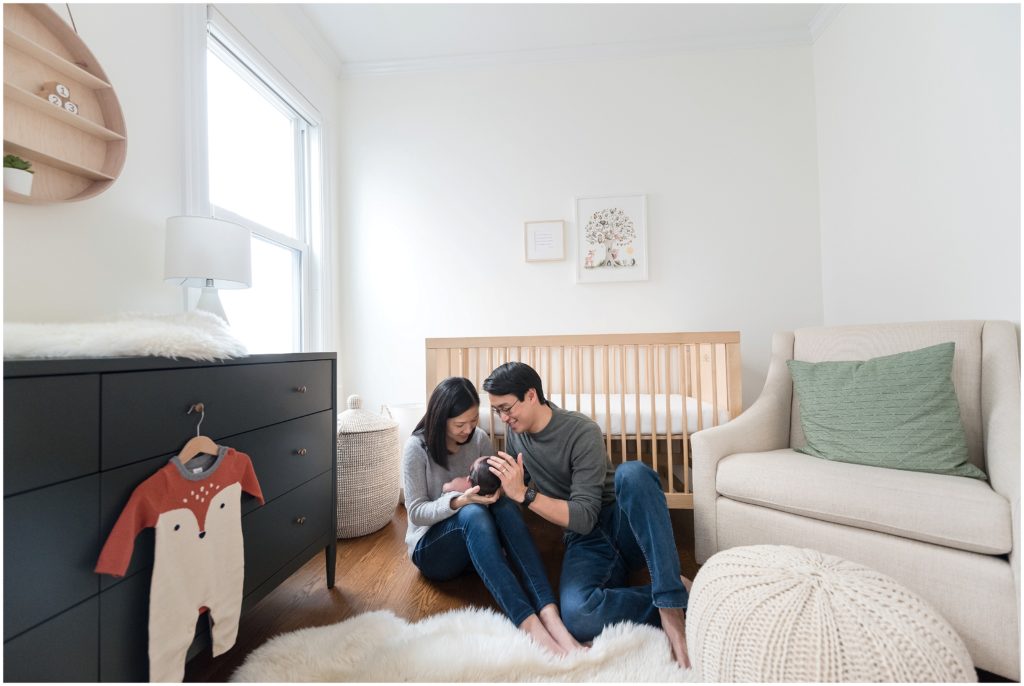 Family sitting in nursery holding newborn during family session at home