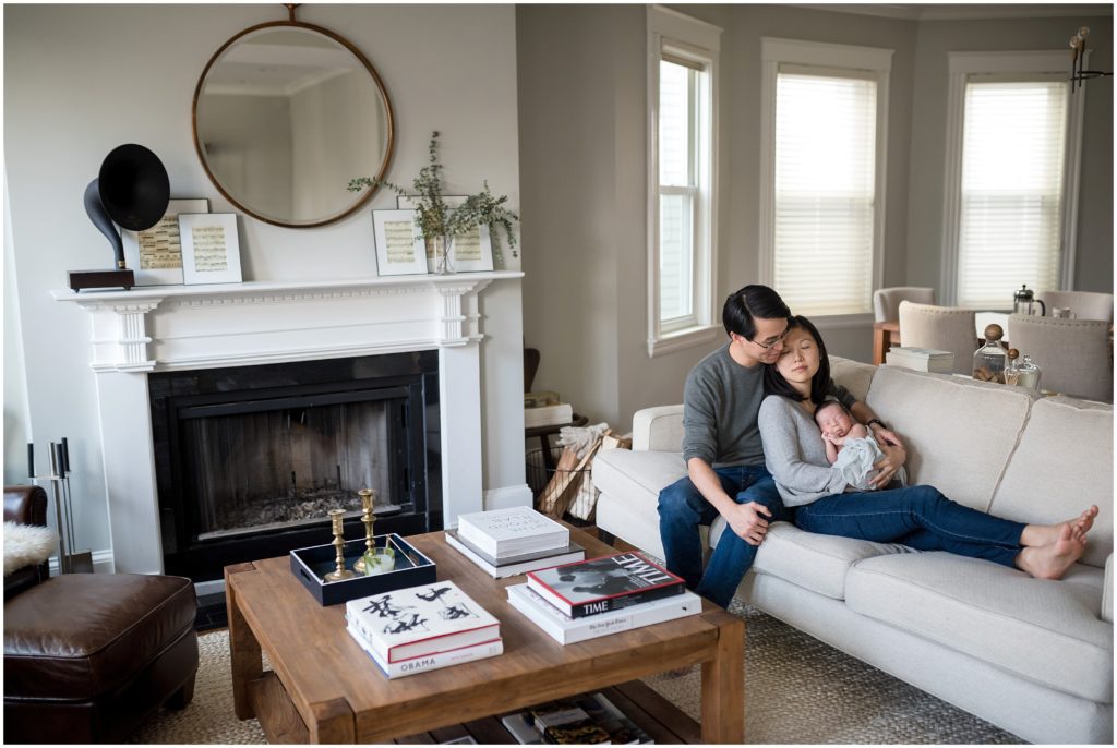 Newborn being held by parents in living room at home during lifestyle session in Cambridge