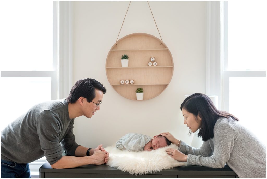 Newborn in his nursery being looked at by his mom and dad