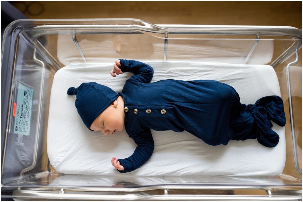 Newborn in knotted onesie in bassinet at hospital