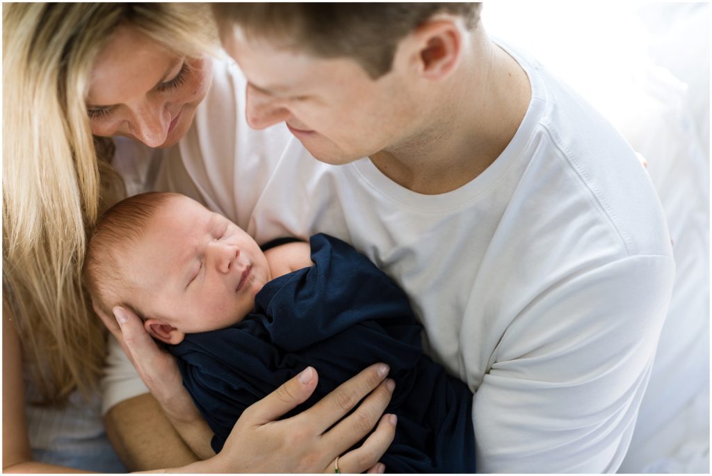 parents holding baby boy on bed