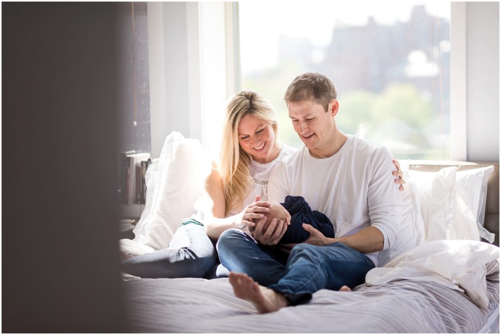 parents holding baby boy in apartment in Boston with state house in background