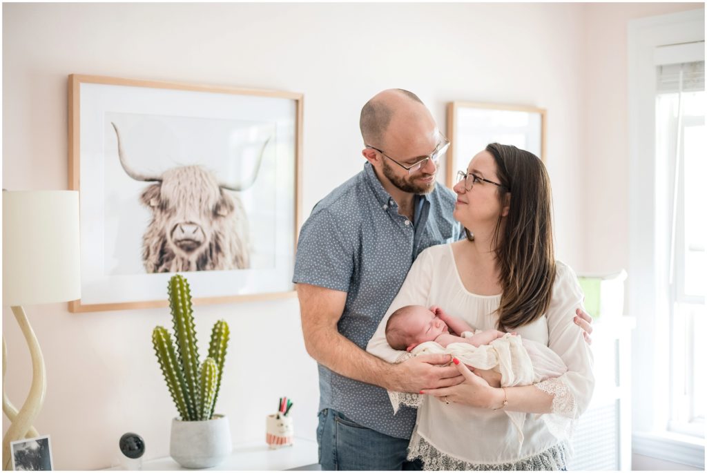 Parents holding baby girl in home in Newton newborn lifestyle session 