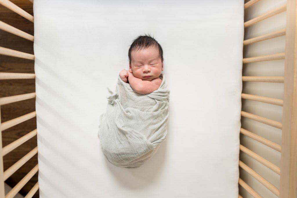 Newborn in crib on back in nursery
