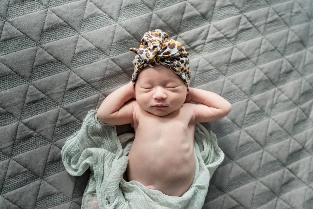 Newborn posed on back on bed