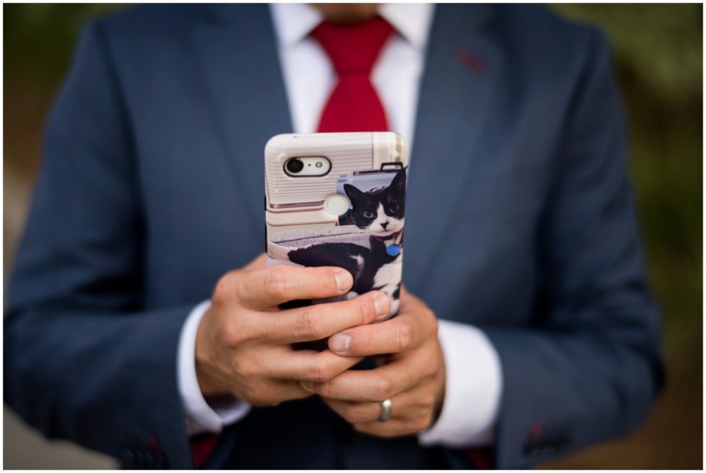 cat on phone case in groom's hands