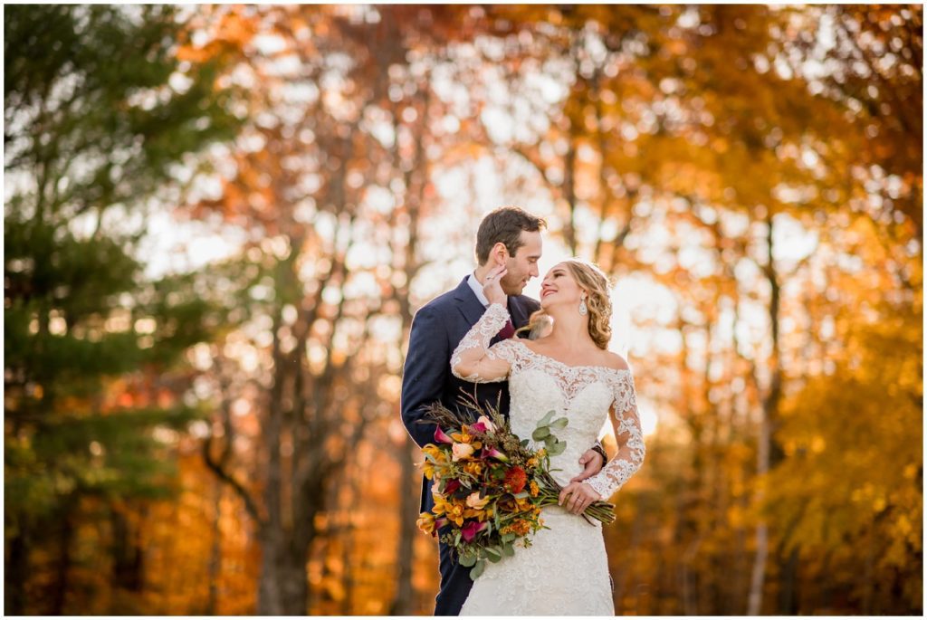 Bride and groom against orange fall leaves outdoors after wedding ceremony portraits