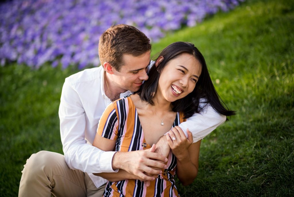 Fiancee smiling while being hugged by fiance on Cambridge City hall lawn