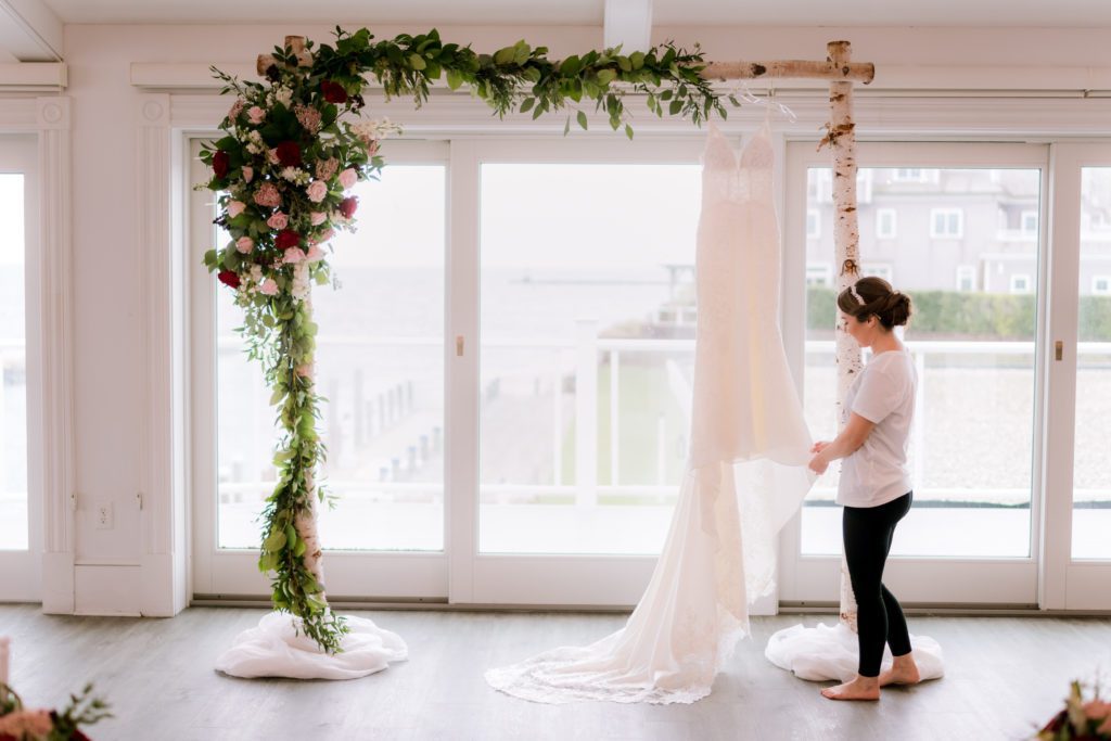 Bride looking at her dress on the arbor